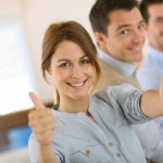 Cheerful girl in office showing thumbs up